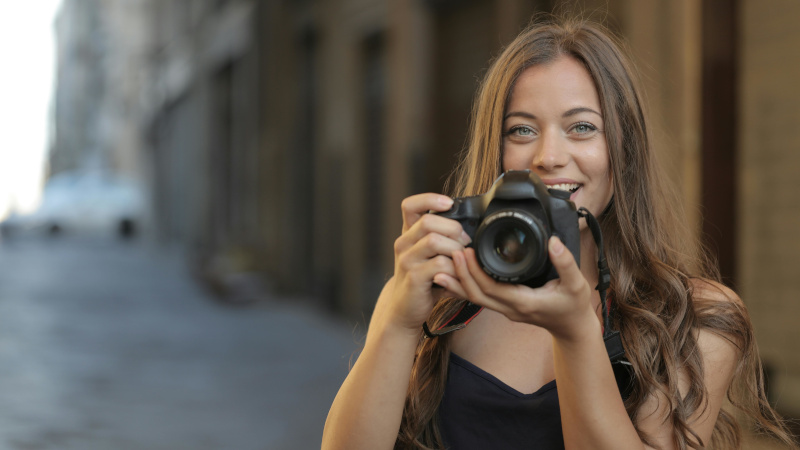 Девушка позирует с фотоаппаратом в руках