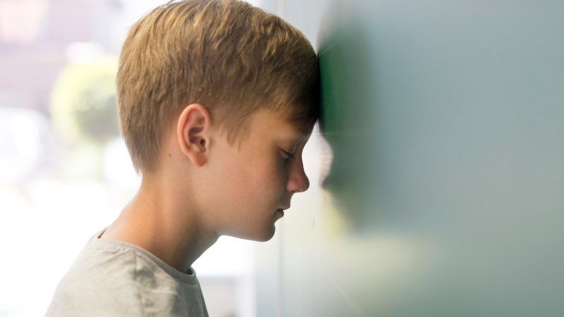 Мальчик уперся лбом в стену