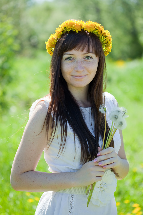 молодая девушка, позирующая на фоне зелёного луга