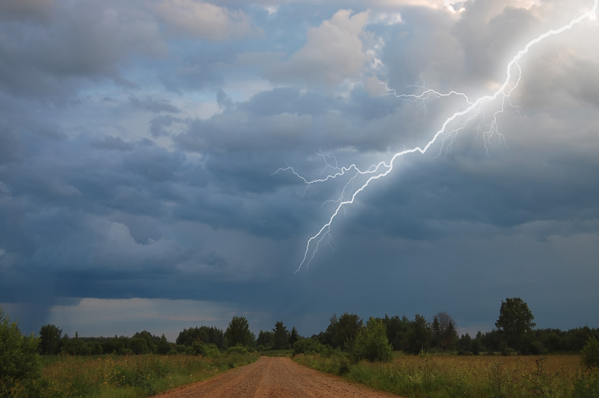 Грозовая туча, яркая молния, грунтовая дорога, зелёные поля.