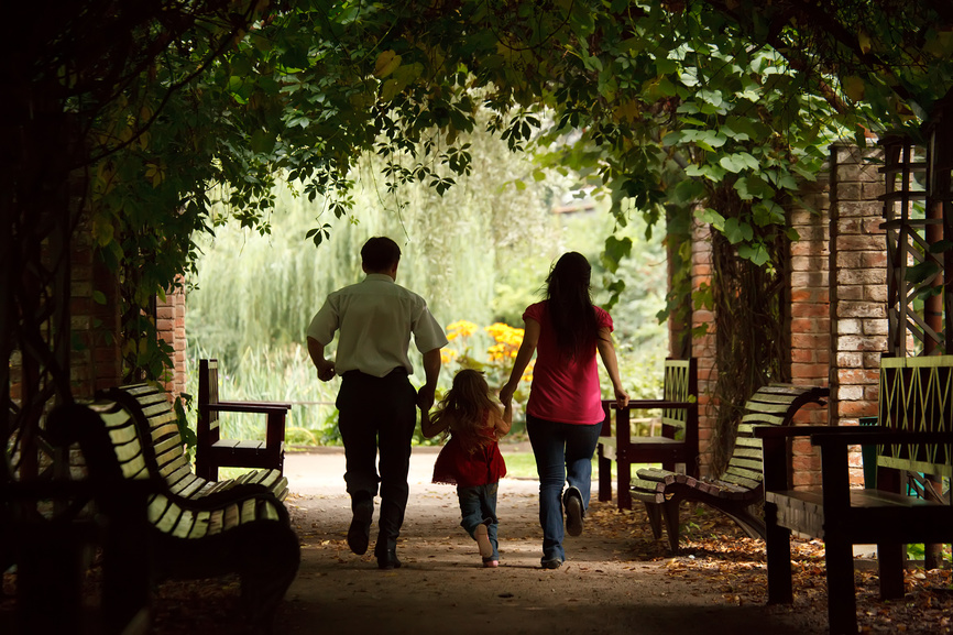 Семья на прогулке в парке под аркой, заросшей диким виноградом