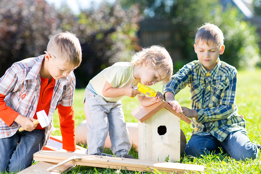 Трое мальчиков на траве собирают скворечник.