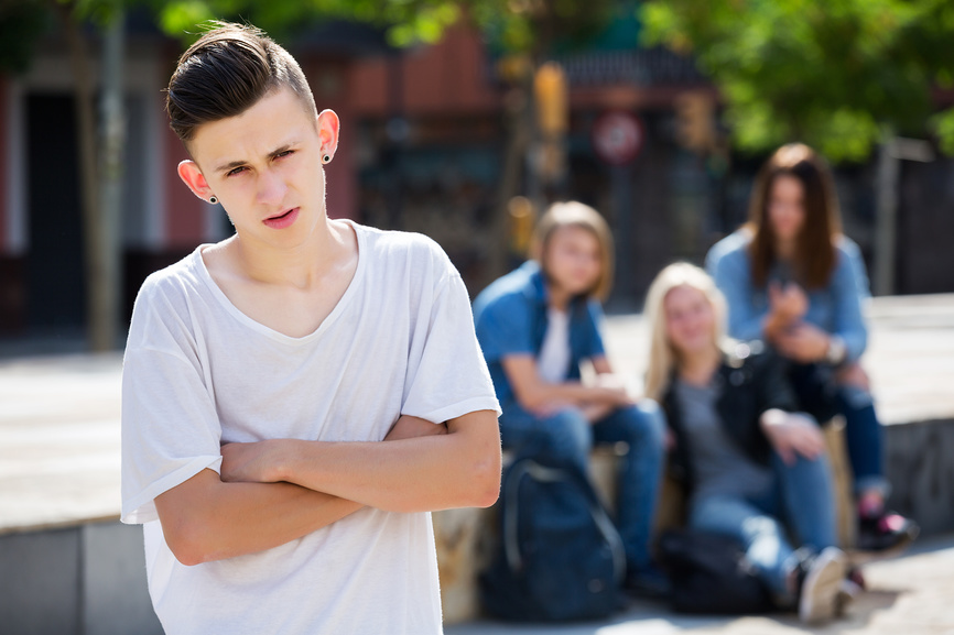 Одинокий подросток стоит в стороне