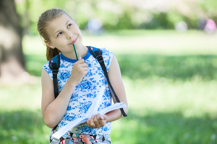 девочка школьного возраста на фоне зелёного парка или сада