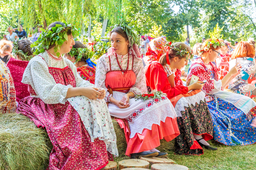 Россия Самара август 2019 года: Фестиваль цветов. На связках соломы сидят девушки в национальных русских костюмах.