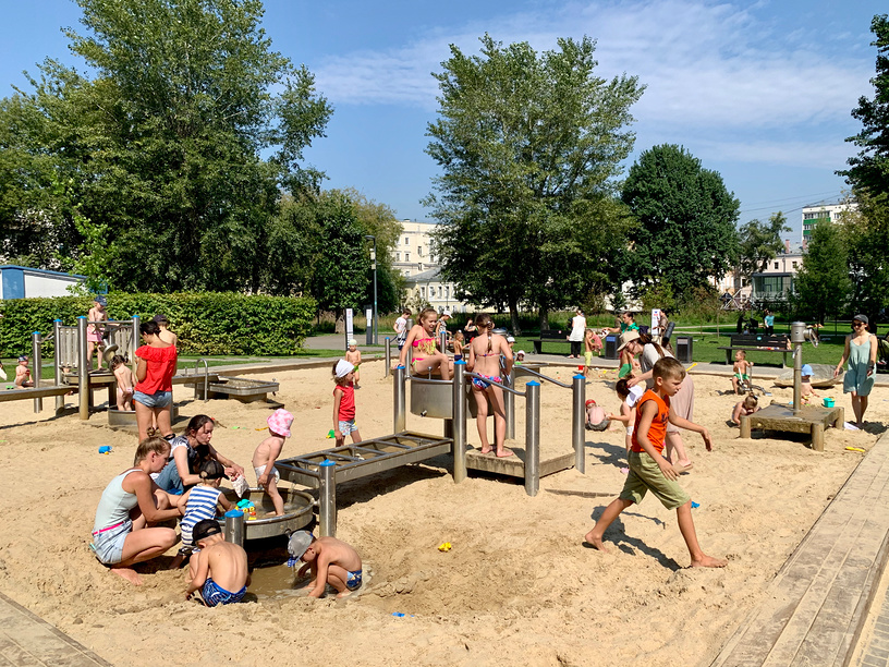 Дети играют в большой песочнице в детском парке