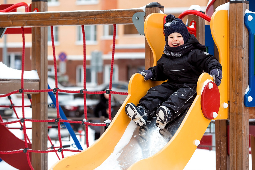 Ребенок весело катается с горки.