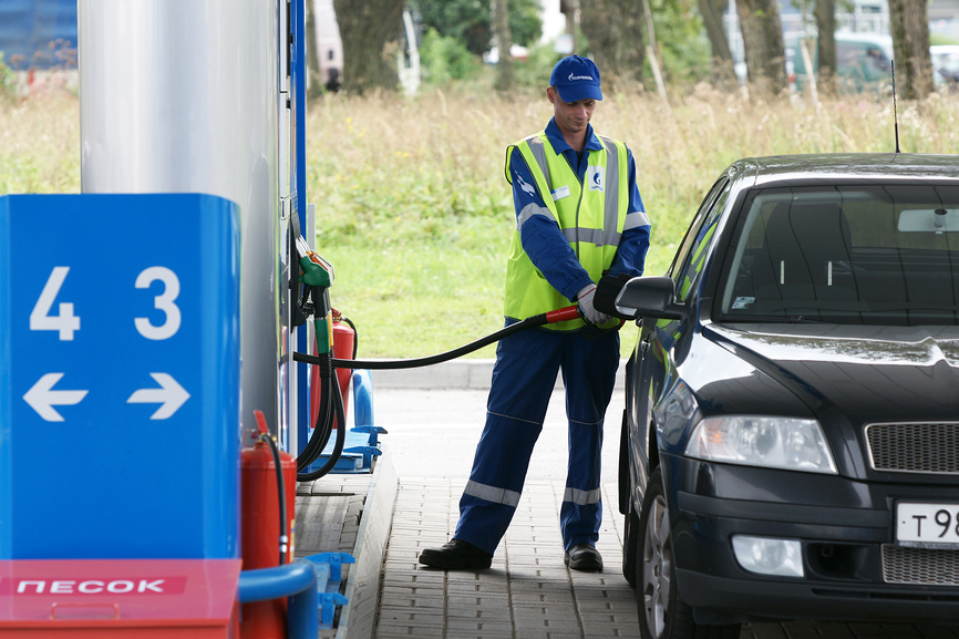 Россия. Санкт-Петербург. Оборудование автомобильной топливной заправки. Сотрудник АЗС заправляет автомобиль бензином. 