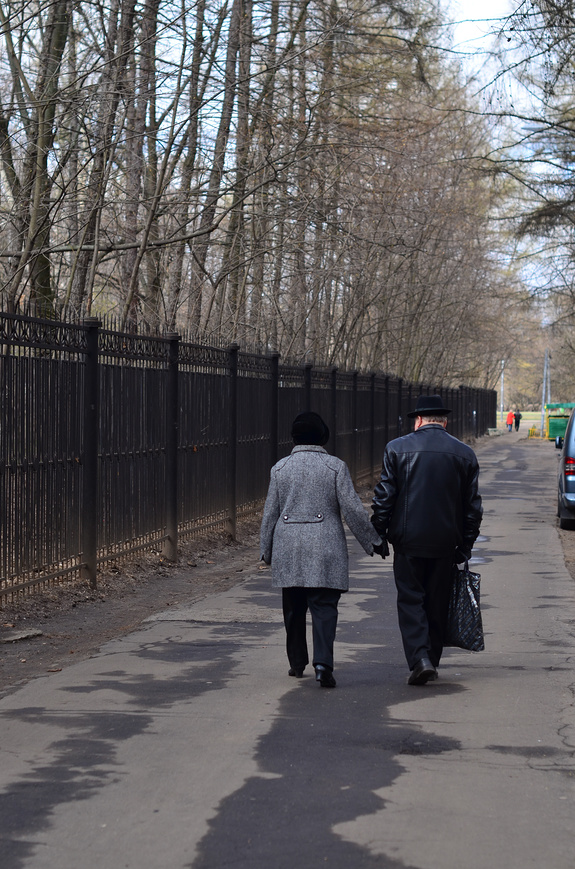 Пожилая пара за руку прогуливается по городу