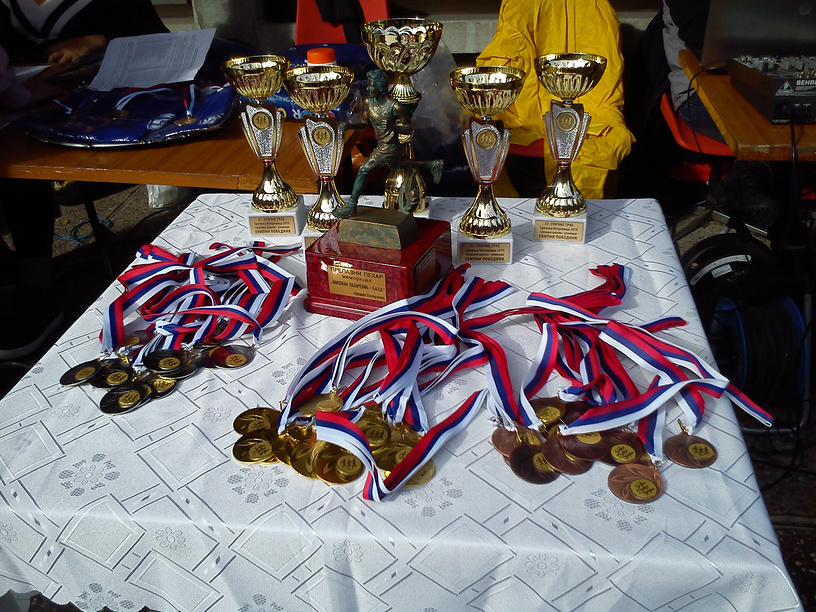 стол, накрытый белой скатертью, на котором разложены спортивные награды: