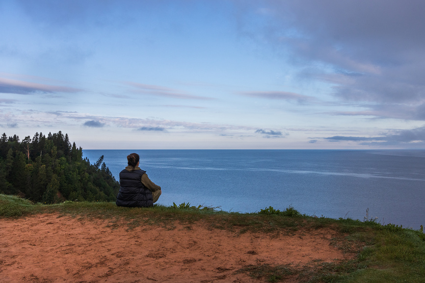 Девушка сидит на краю обрыва смотрит вдаль, Андомский мыс (Андома-гора) на Онежском озере