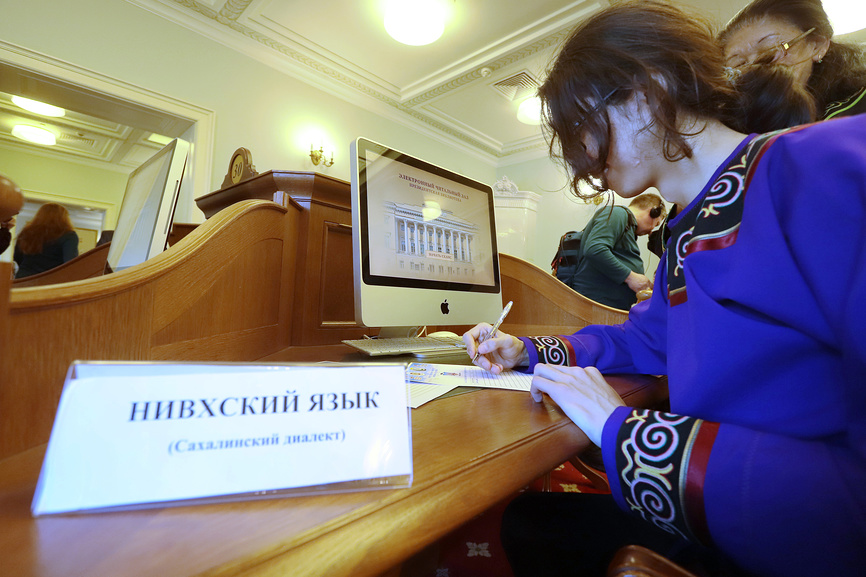 читальный зал Президентской библиотеки им. Б. Н. Ельцина. Человек в традиционной одежде работает за компьютером с табличкой Нивхский язык 